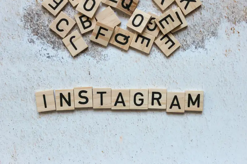 Wooden letter blocks arranged to spell 'Instagram' on a textured surface.